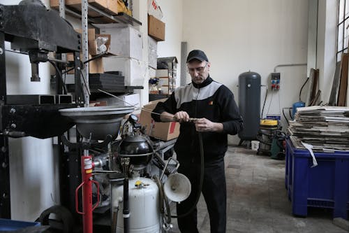 Focused mechanic repairing compressor hose in workshop