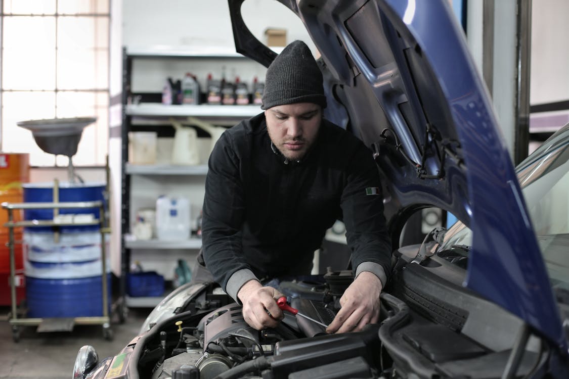 Free Man in Black Jacket and Black Knit Cap Standing Near Vehicle Stock Photo