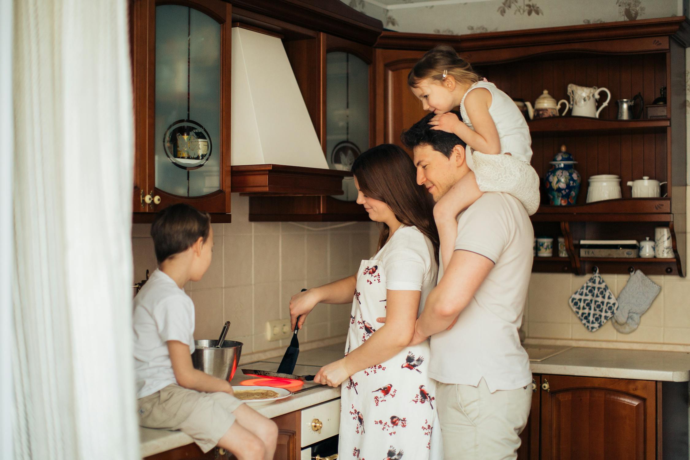Family of four making pancakes in the kitchen.