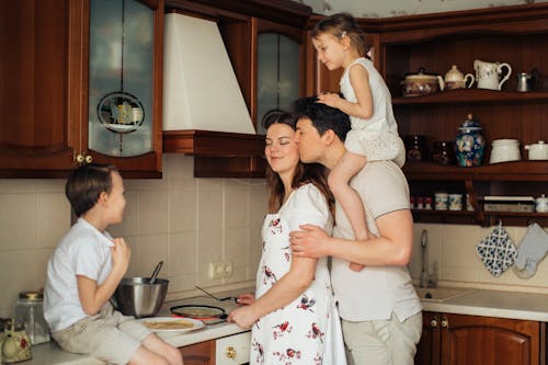 Photo of Man Kissing His Wife While Cooking