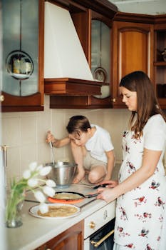 A mother and her child cooking pancakes together in a cozy home kitchen.