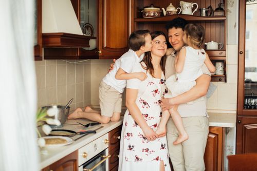 Free Joyful family moment embracing in a warm kitchen setting with smiles and affection. Stock Photo