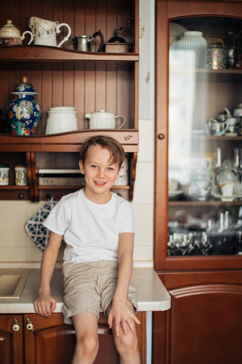 Foto Anak Laki Laki Yang Duduk Di Meja Dapur Sambil Tersenyum