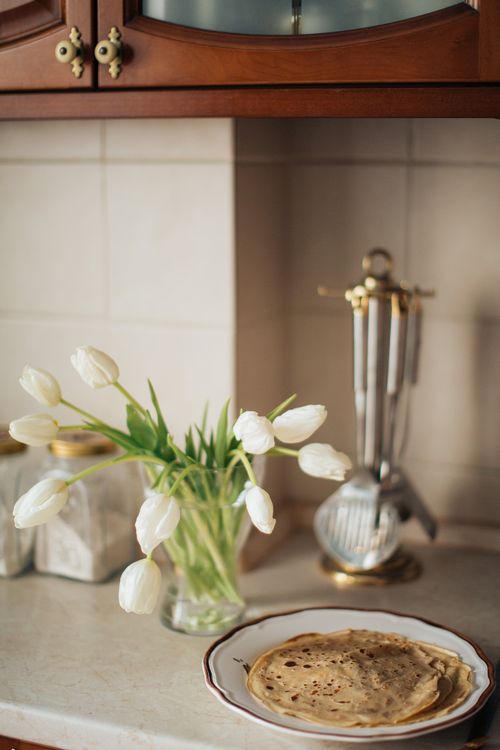 Free Warm, inviting kitchen scene featuring homemade crepes and white tulips, perfect for a traditional celebration. Stock Photo