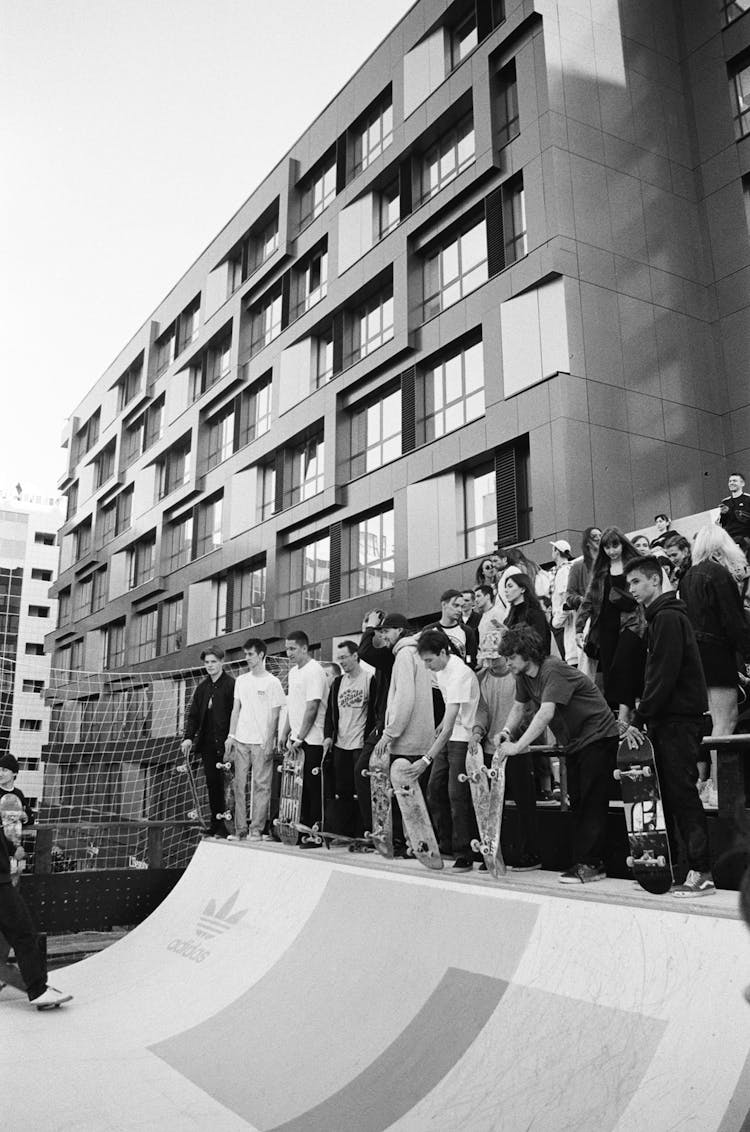 Grayscale Photo Of People Standing On Skatepark