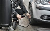 Man in Black Jacket and Black Pants Sitting Near Silver Vehicle