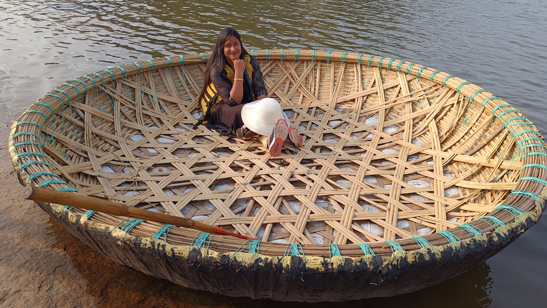 A woman sitting in a traditional coracle boat on the Tungabhadra River in Hampi, India.