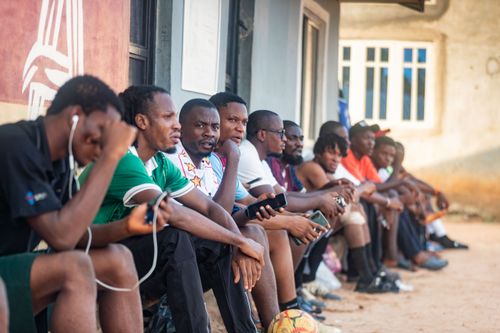 Free A diverse group of men sitting outdoors, focused on their smartphones with a casual and relaxed vibe. Stock Photo