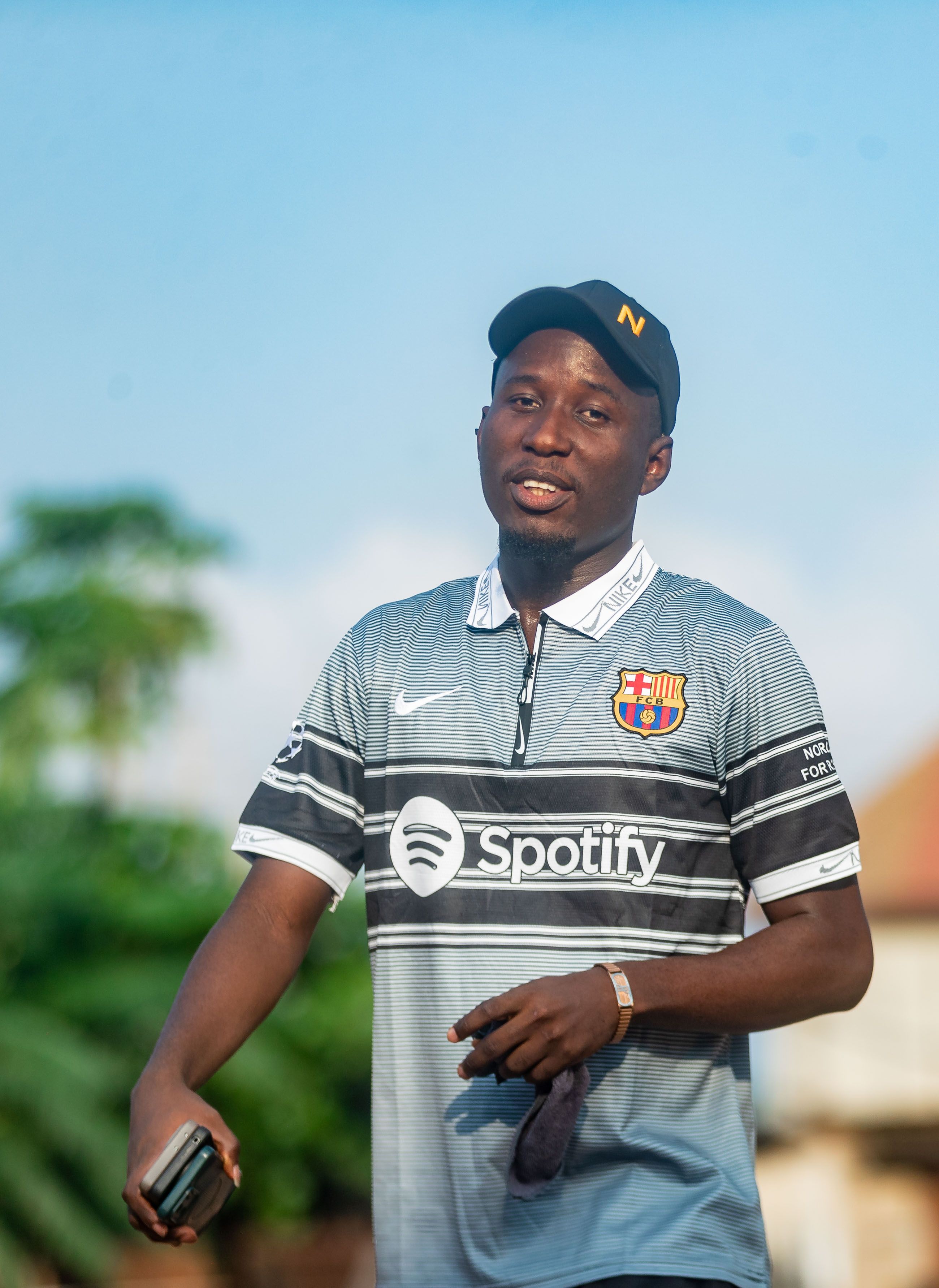 Young man in a sports jersey and cap outdoors on a sunny day.