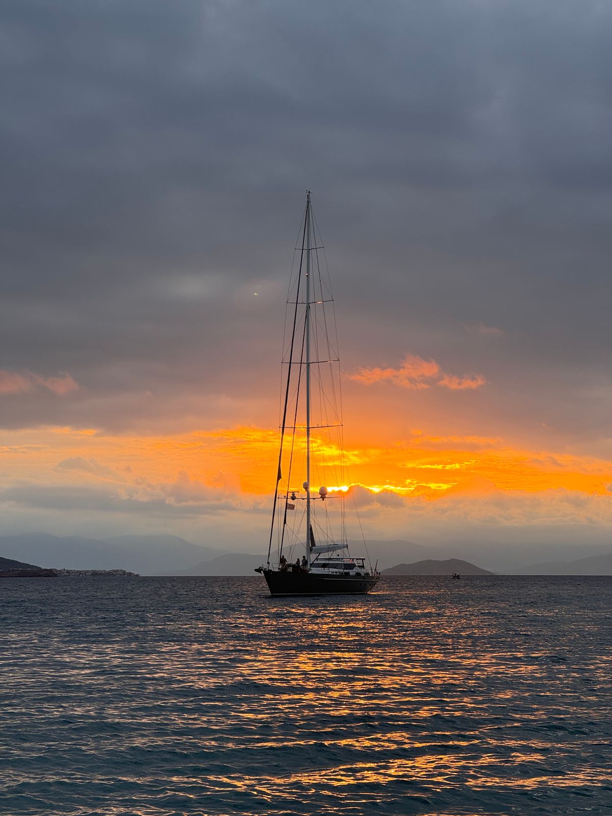 A sailing yacht anchored in calm water at sunset