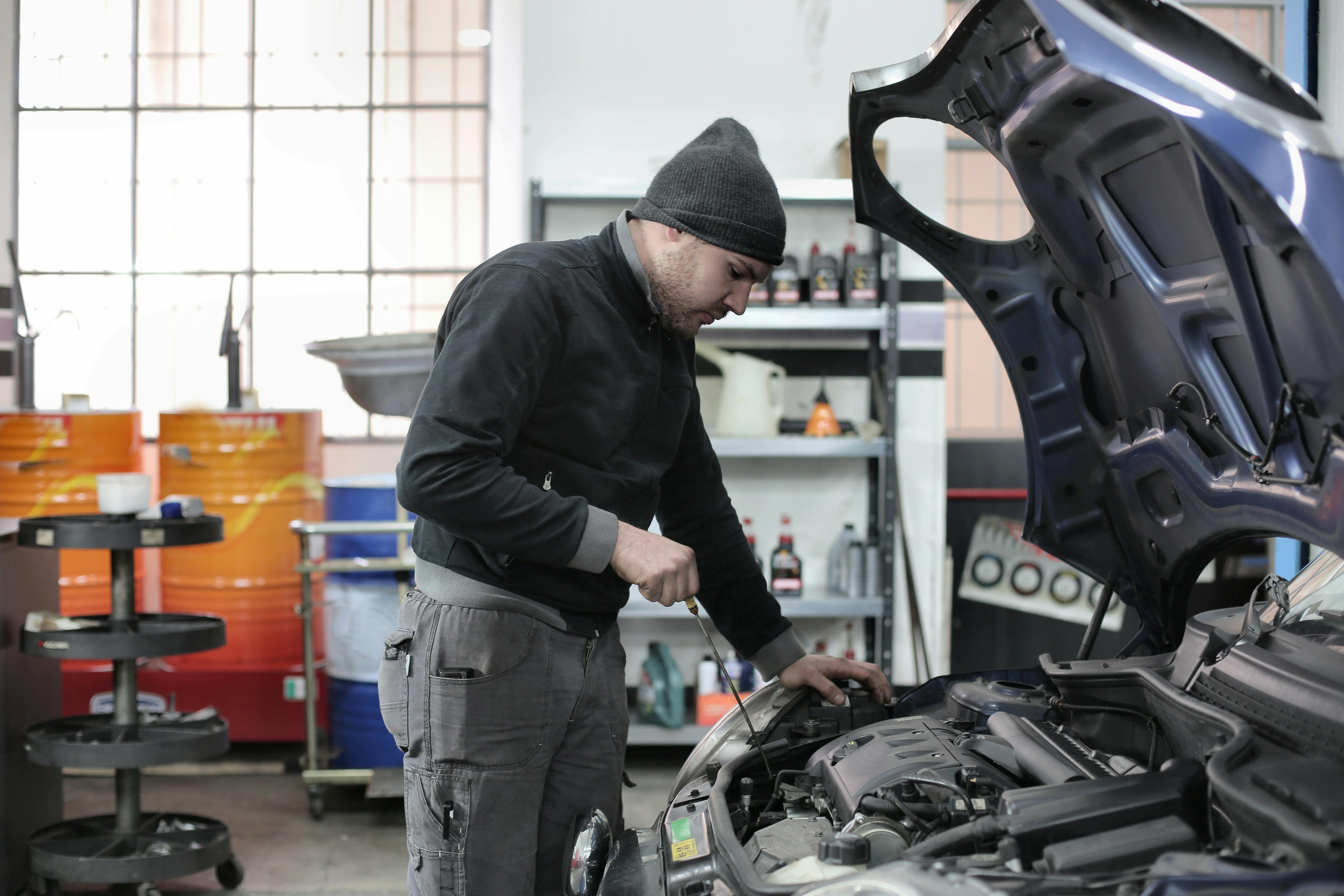 photo of man inspecting car engine