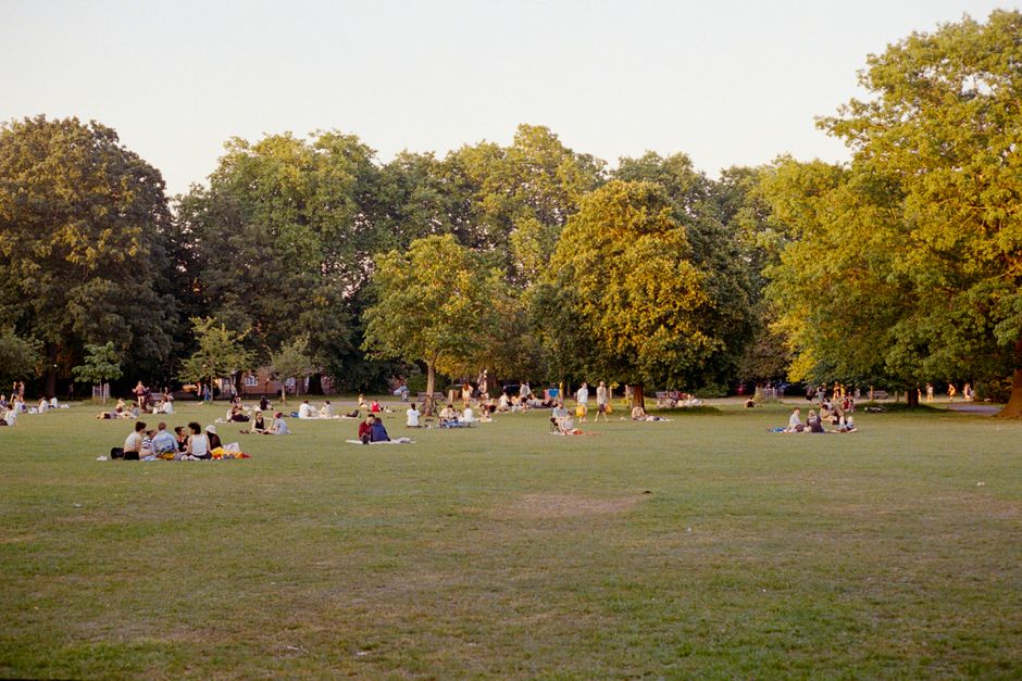 A vibrant park scene with groups of people enjoying a sunny summer day outdoors.
