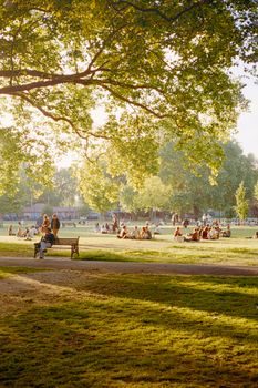 People relaxing in a sunny park, enjoying the serenity of nature and community gathering.