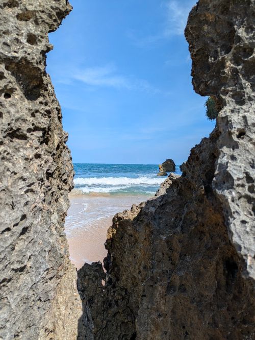 Free Scenic ocean view framed by rough rock formations on a sunny day in Jogja, Indonesia. Stock Photo