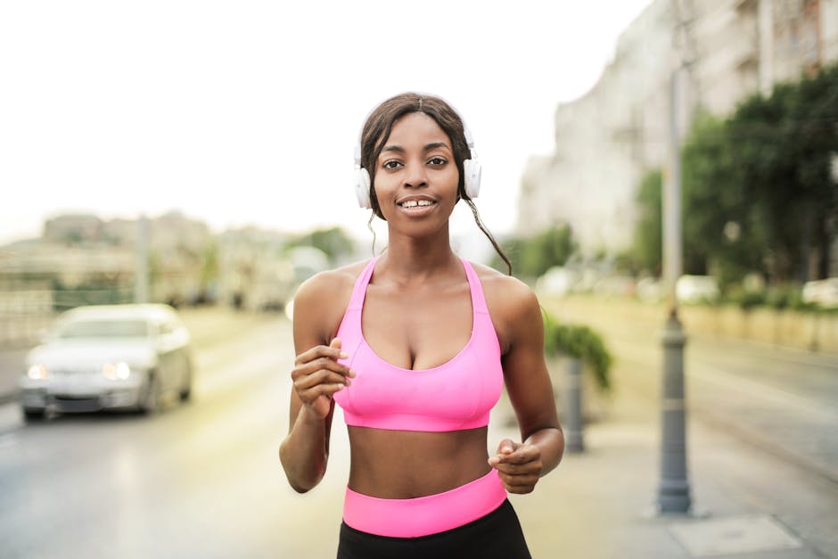 A woman in a pink sports bra jogging outdoors with headphones, embodying a healthy lifestyle.