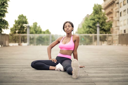 Young woman in pink sports bra and black leggings stretching outdoors on a wooden deck.