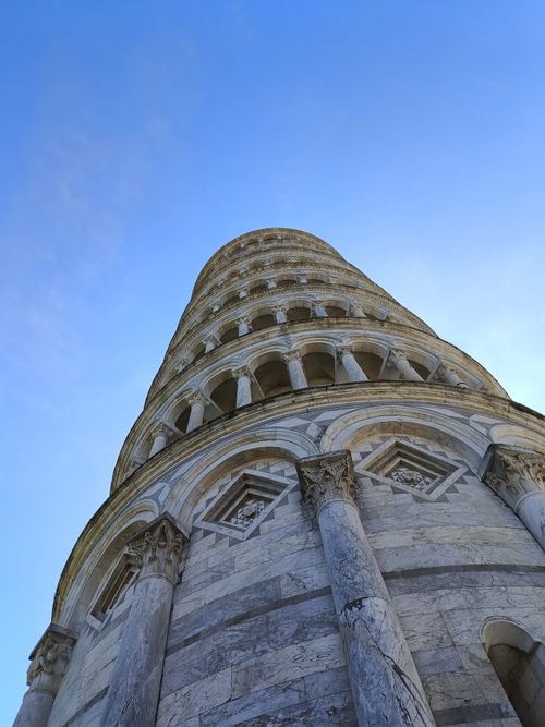 Free The Leaning Tower of Pisa captured from a unique upward angle against a clear blue sky in Italy. Stock Photo