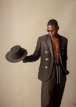 Portrait of an elegantly dressed man holding a black fedora, showcasing modern fashion.