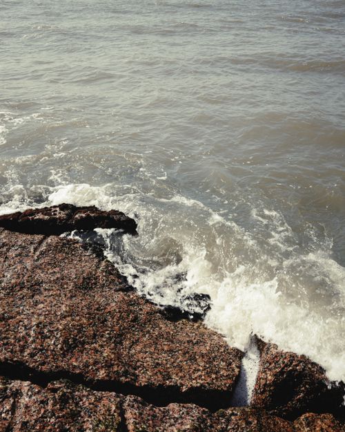 Free Rugged rocks meet gentle waves on a coastal shoreline in Galveston, Texas. Stock Photo