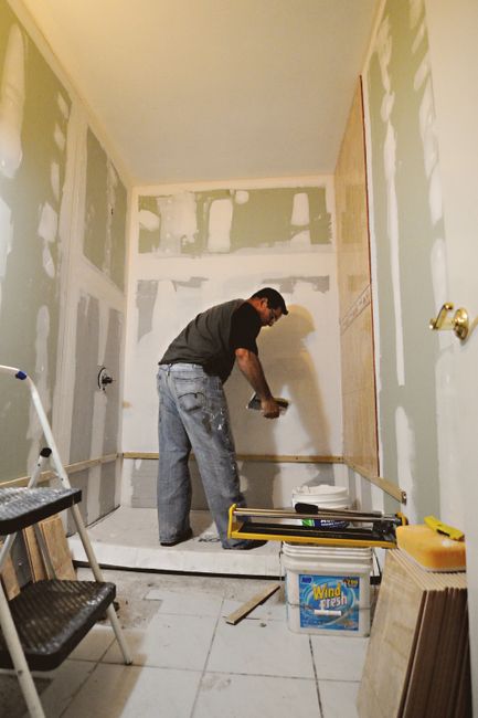 Photo by DΛVΞ GΛRCIΛ on Pexels A man working on a bathroom renovation, applying drywall mud on interior walls.