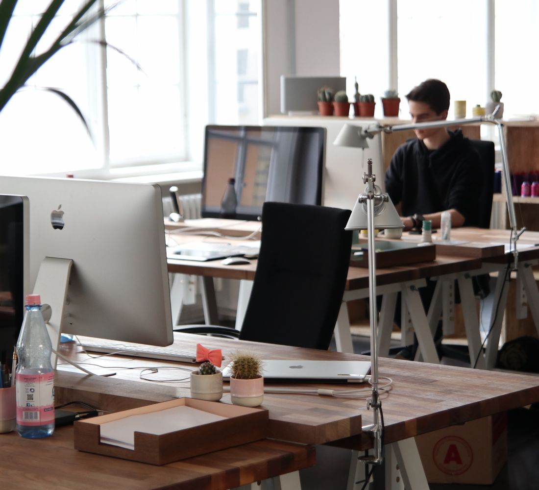 A bright office where people work across large desktop screens