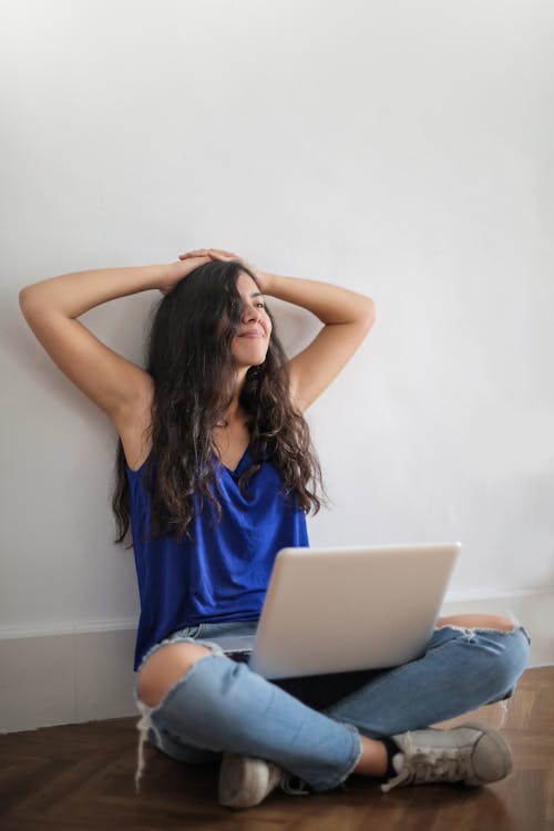 Free Positive woman sitting with laptop in room Stock Photo