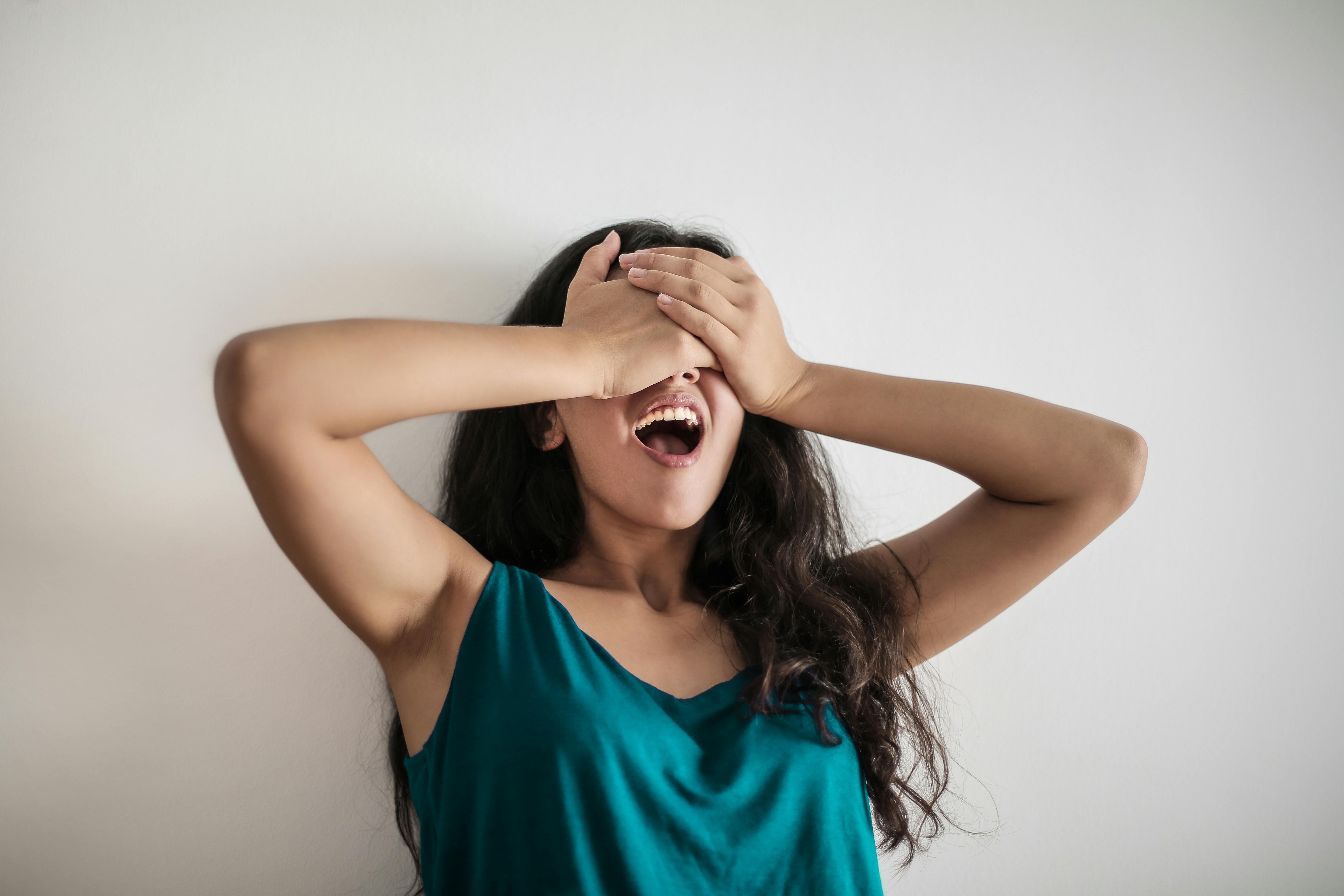 expressive woman covering eyes by hands