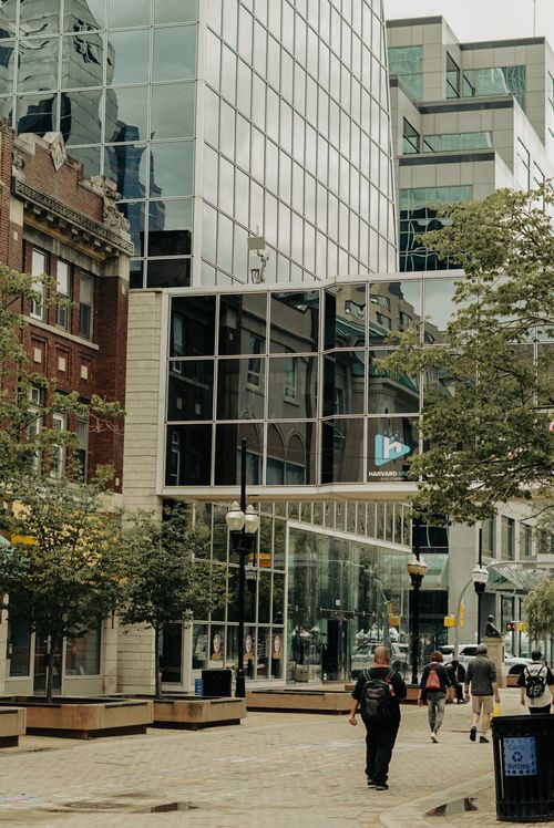 Free A bustling city street lined with modern glass buildings and pedestrians walking. Stock Photo