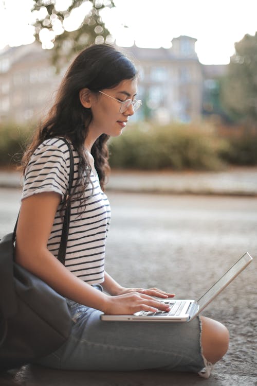 Woman in White and Black Striped Shirt While Using Laptop