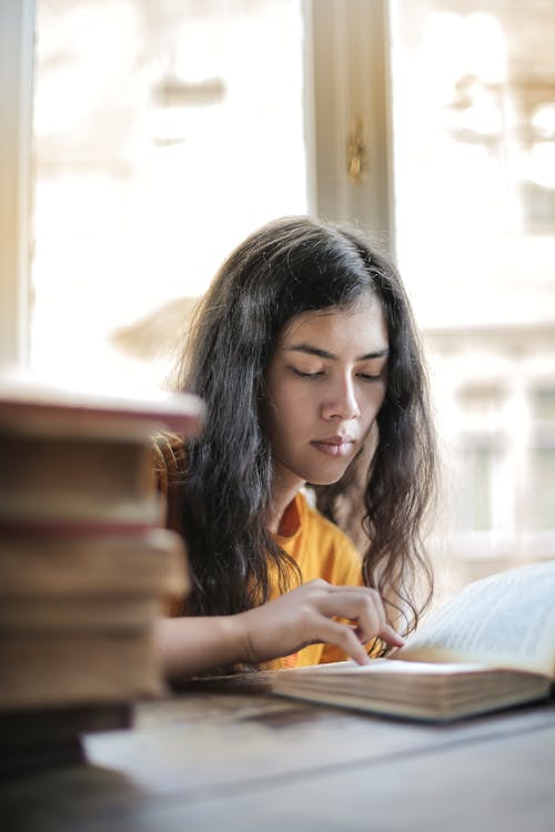 Smart woman reading book at table