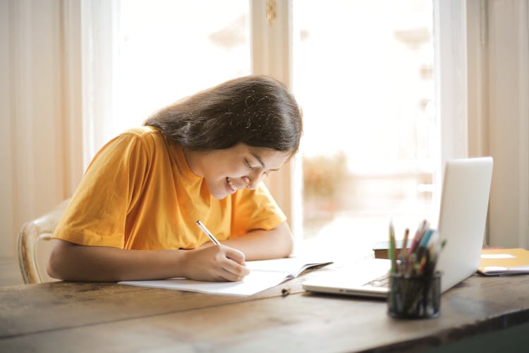 Woman In Yellow Shirt Writing On White Paper