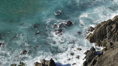 Free Aerial shot of turquoise ocean waves crashing against rocky cliffs, creating a stunning coastal scene. Stock Photo