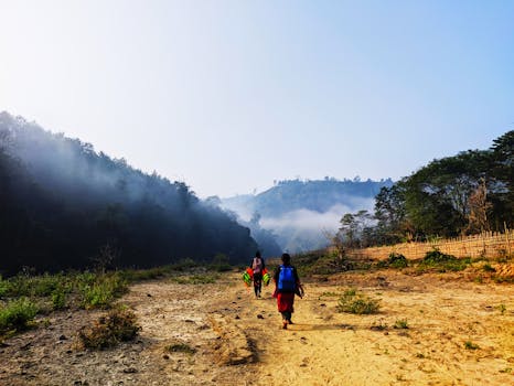 Two hikers traverse a foggy landscape in the scenic hills of Bandarban, Bangladesh.