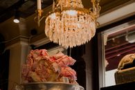Elegant crystal chandelier casting warm light over a large bowl of indulgent dessert in a stylish setting.