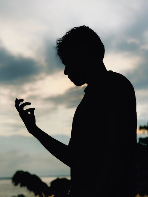 Free A captivating silhouette of a person contemplating at sunset by the sea. Stock Photo