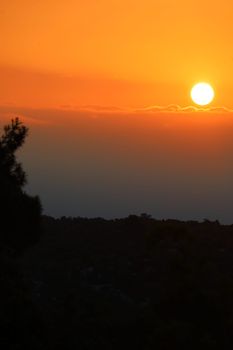 Dramatic sunset with vivid orange sky above silhouetted hills.