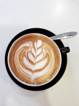 Top-down view of a cappuccino cup featuring intricate latte art on a smooth surface.