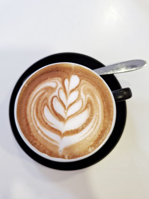 Free Top-down view of a cappuccino cup featuring intricate latte art on a smooth surface. Stock Photo
