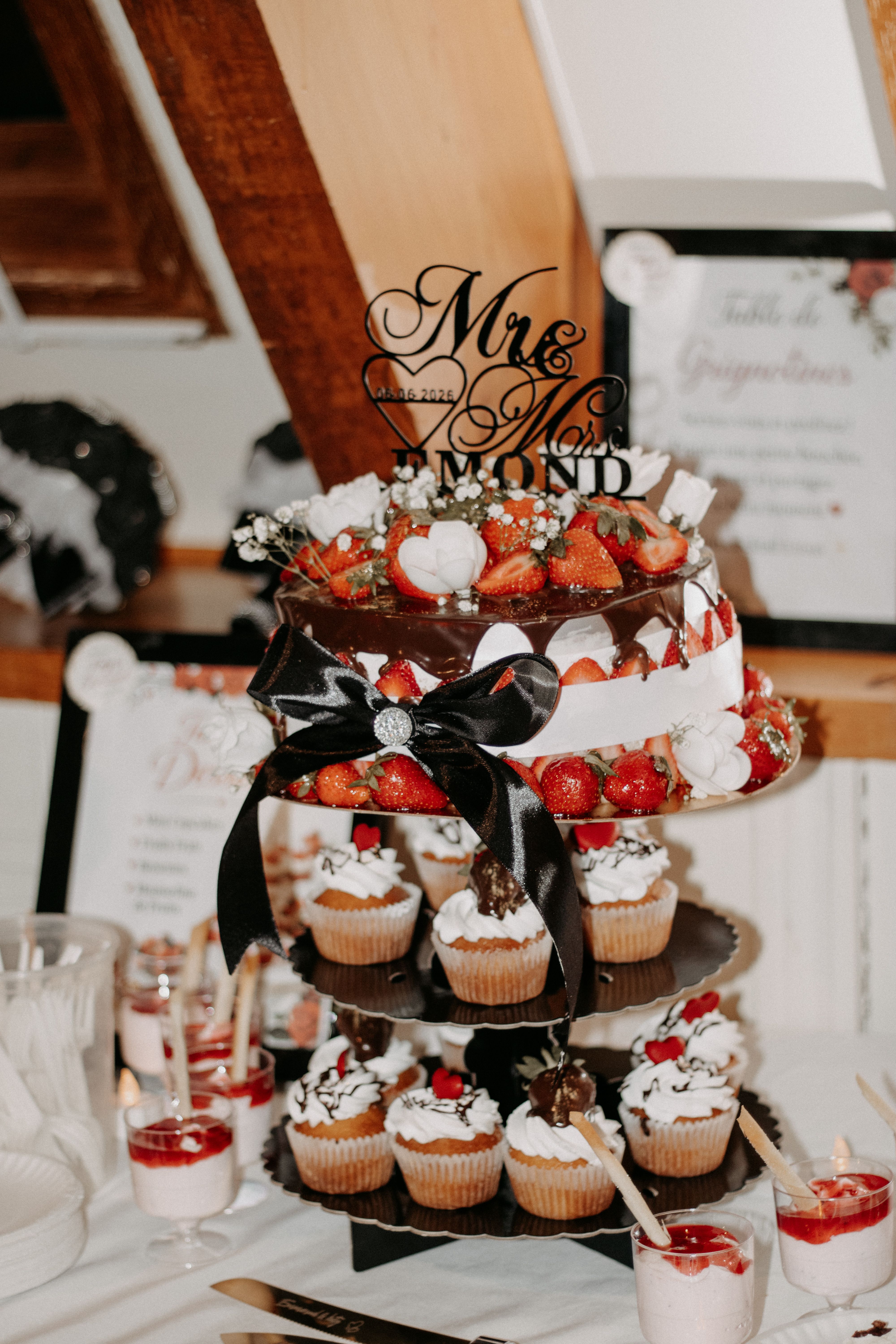 Elegant wedding dessert display featuring a tiered cake with strawberries and cupcakes, perfect for celebrations.