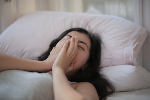 Free Woman Lying on Bed Covering Her Face With Her Hands Stock Photo