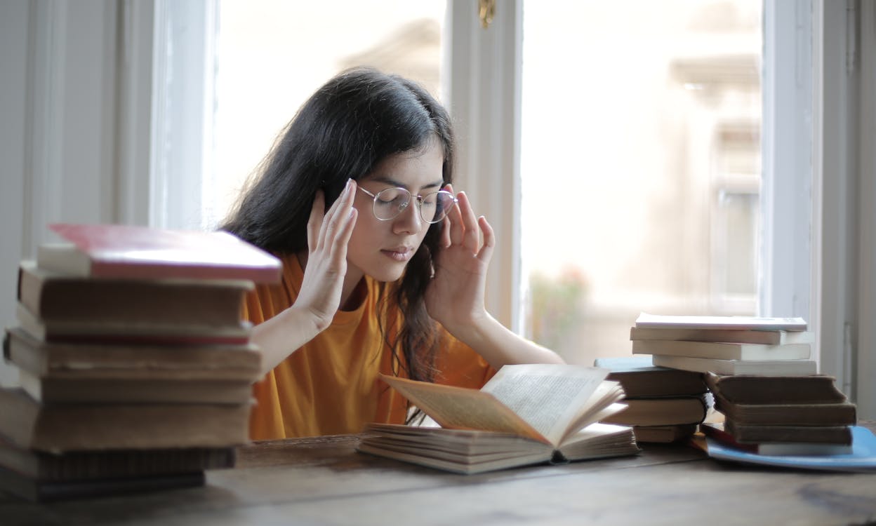 Female student suffering from headache in library