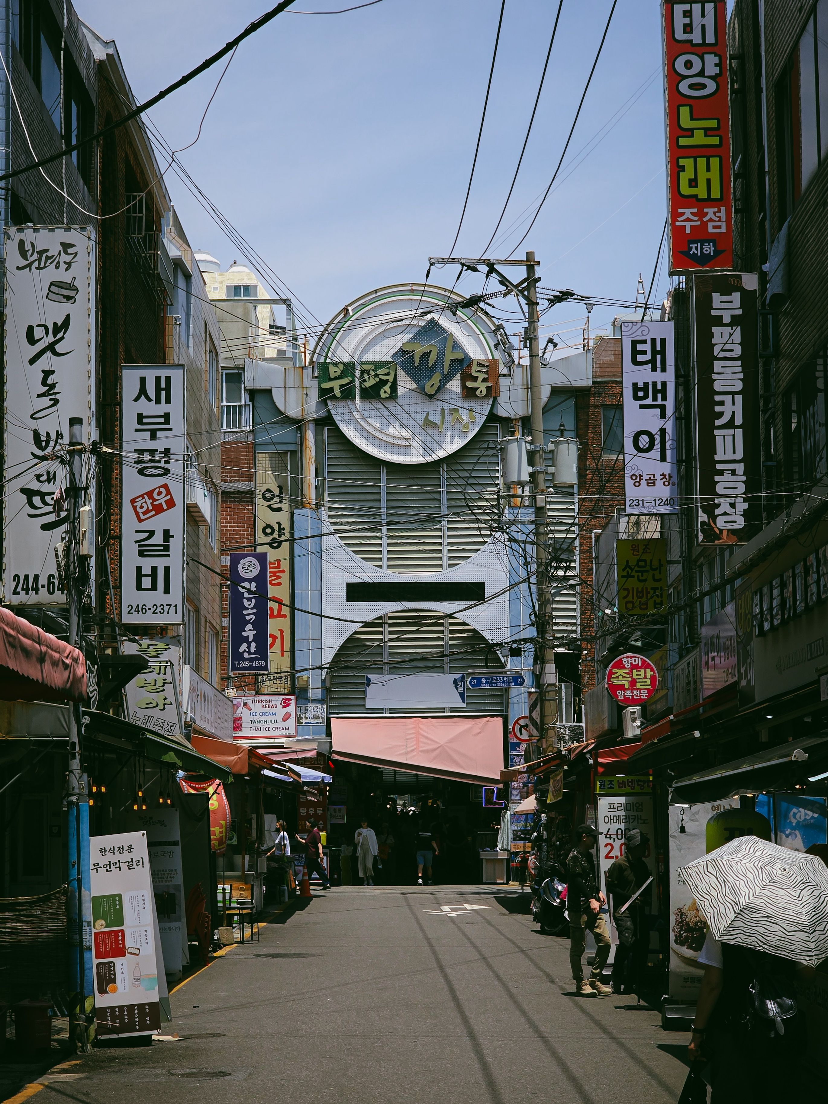 Vibrant street market scene in Busan with colorful signs and busy shoppers.