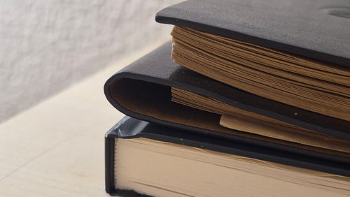 Free A stack of vintage books with textured leather covers and yellowed pages on a wooden surface. Stock Photo