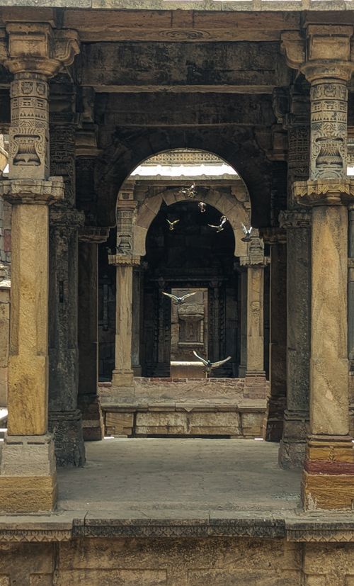 Free A view through detailed stone arches in ancient architecture, capturing birds in mid-flight. Stock Photo