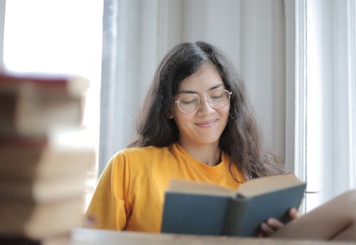 Vrouw In Geel Overhemd Glimlachen Tijdens Het Lezen Van Een Boek