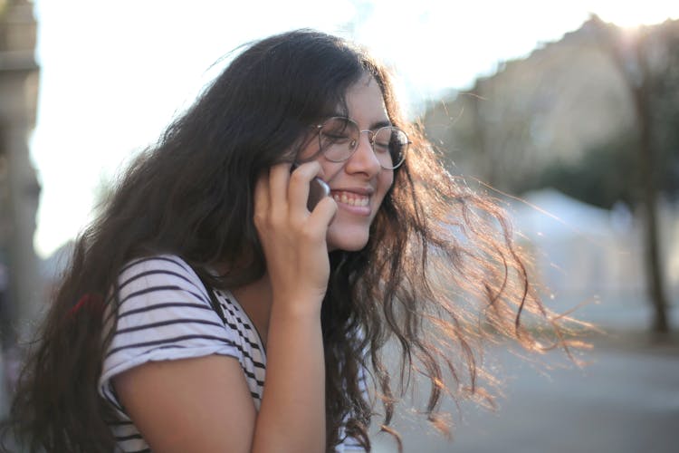 Positive Woman Speaking On Smartphone On Street