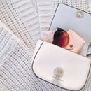 Trendy handbag with sunglasses on knitwear