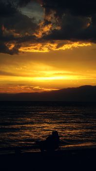 A striking silhouette of a person on a beach set against a dramatic sunset sky.