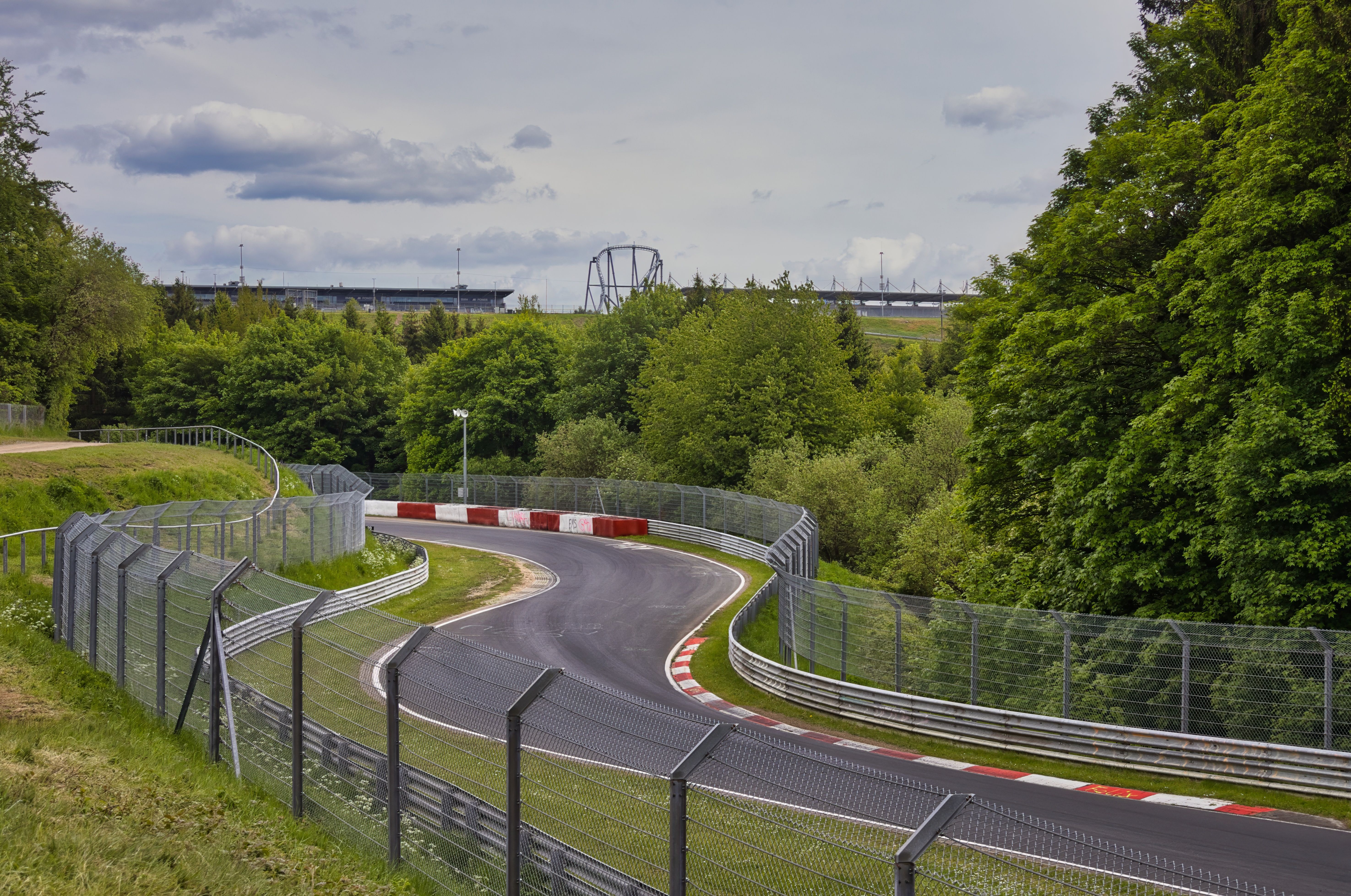 Scenic view of a curving race track at the Nürburgring, surrounded by lush greenery.