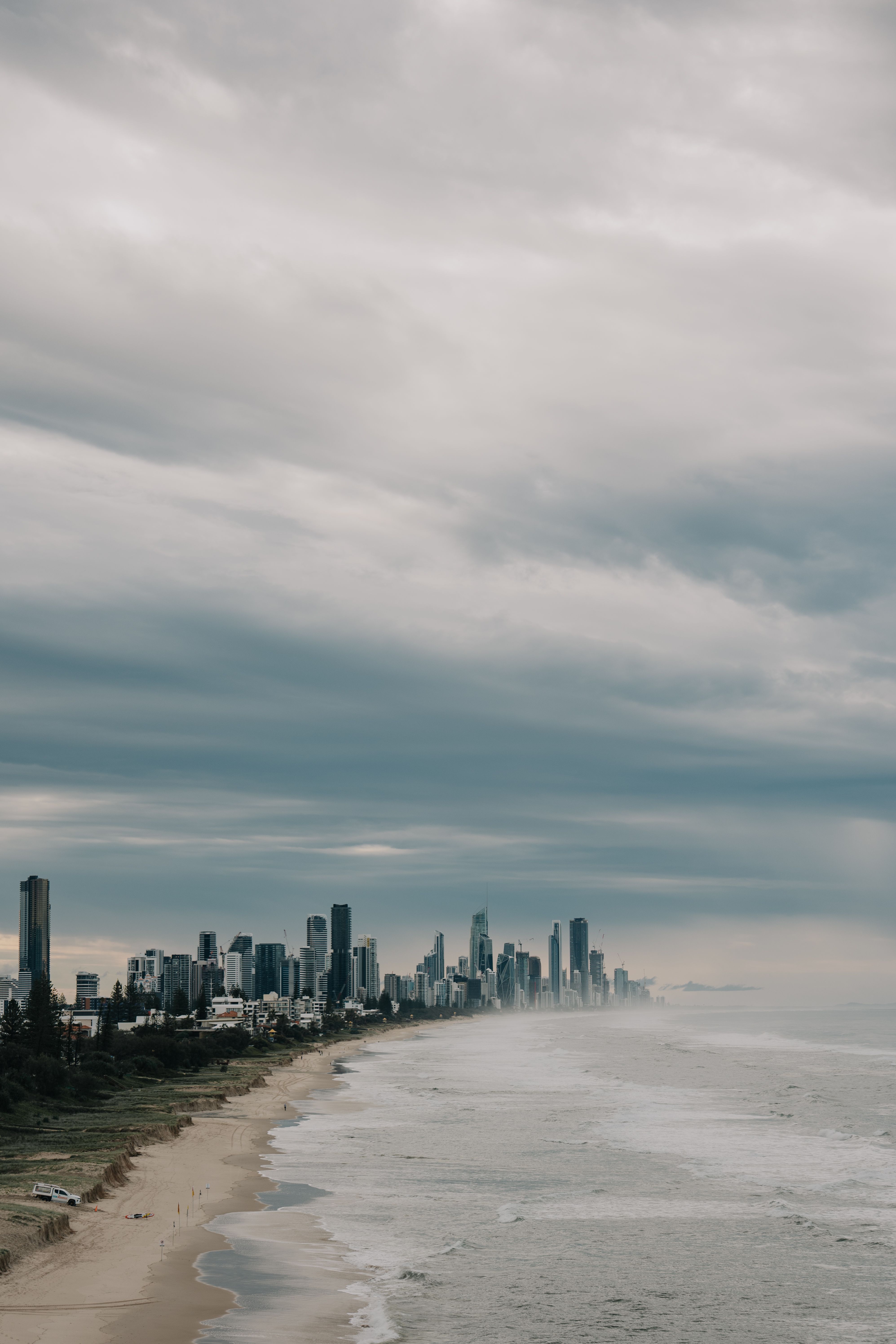 Stunning view of Gold Coast skyline with overcast skies and ocean waves.